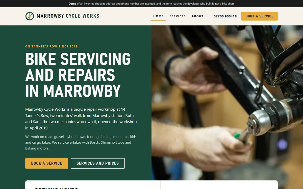 The top of a bicycle repair workshop's home page under a dark demo notice: its name, menu, phone number and Book a service button, the headline Bike servicing and repairs in Marrowby over a short description on dark green, a photograph of hands fitting a part to a black bike frame, and the top of the opening hours card.